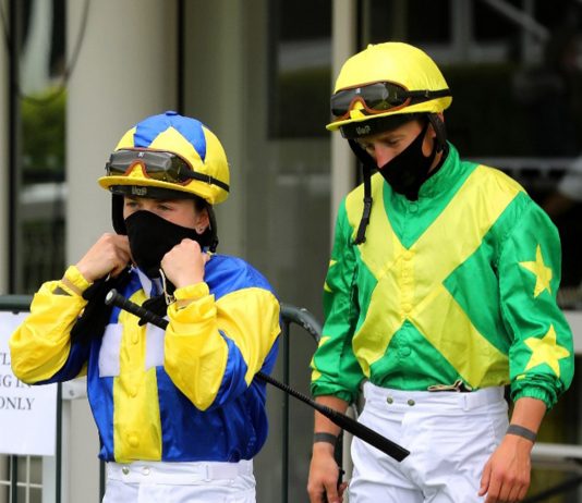Masked jockeys following the return of racing.