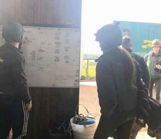 Jockeys look at the riding out chart at Philip Kirby racing stables, in the wake of the coronavirus. Photo: courtesy Philip Kirby.