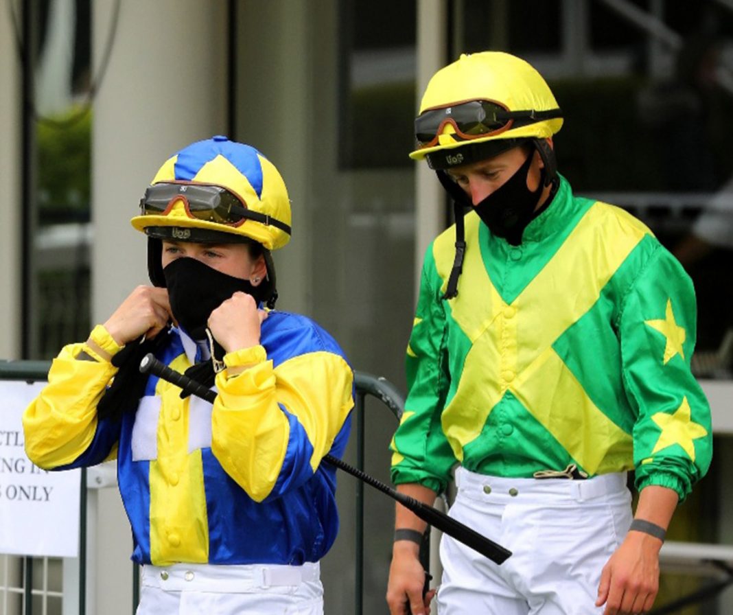 Masked jockeys following the return of racing.